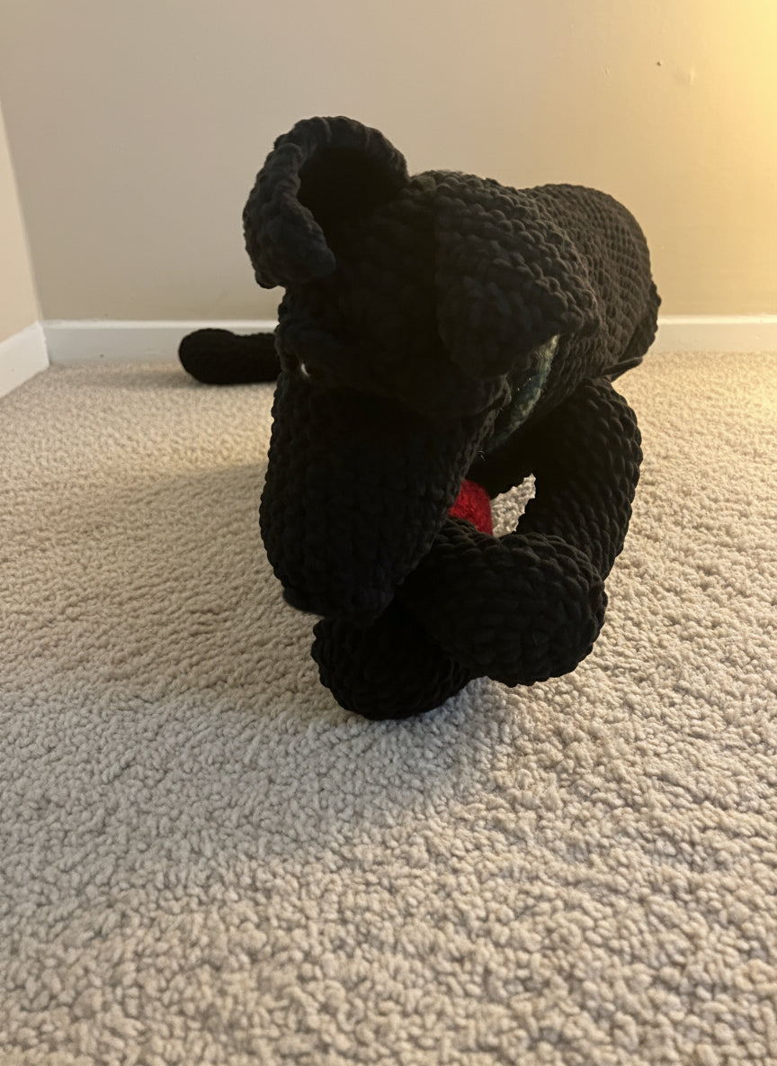 Black crocheted dog toy on a textured carpet